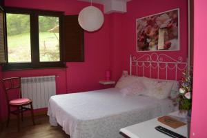 een roze slaapkamer met een bed en een bureau bij el calero in Oviedo