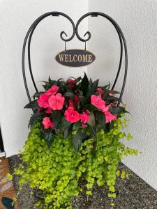 a pot of flowers on a wall with a welcome sign at Shannon Heights B&B in West Kelowna
