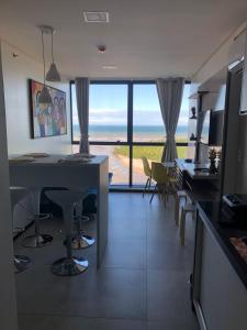 a kitchen with a table and chairs and a large window at FLAT BEIRA MAR BARRA DE JANGADA RECIFE ANDAR ALTO in Recife