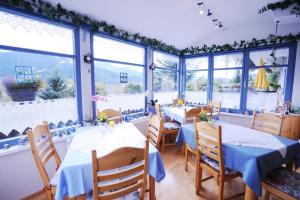 un restaurante con mesas y sillas azules y ventanas en Haus Alpina, en Radstadt