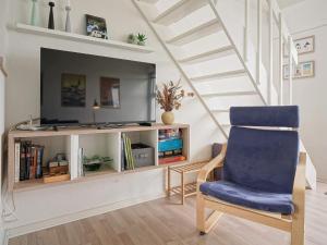 a living room with a tv and a blue chair at Seaside Property in Sandkas in Allinge