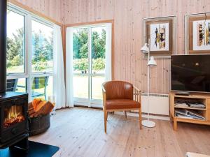 a living room with a fireplace and a chair and a television at 8 person holiday home in Ulfborg in Fjand Gårde