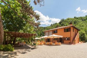 a building with tables and umbrellas in front of it at Agriturismo Rio Verde in Sasso Marconi