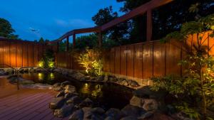 a bridge over a pond in a garden at night at Art Hotel Narita in Narita