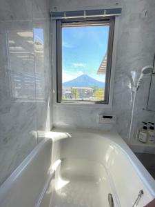 a white bath tub in a bathroom with a window at Necoana Glamping in Fujikawaguchiko