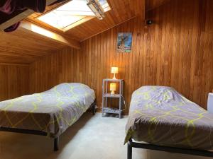 Duas camas num quarto com paredes de madeira e uma clarabóia. em Maison Étel, 3 pièces, 4 personnes - FR-1-397-6 em Étel