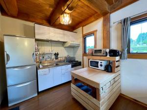 Il comprend une cuisine avec des appareils blancs et un plafond en bois. dans l'établissement 八ヶ岳 HOKUTO BASE -Yatsugatake-, à Hokuto