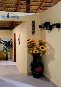 a black vase with yellow flowers in a room at La Casita de Mary in Santa Cruz de Barahona