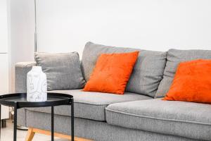 a grey couch with orange pillows and a table at Le Fortia - Vieux-Port 2 chambres avec balcon in Marseille
