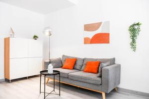 sala de estar con sofá gris y almohadas de color naranja en Le Fortia - Vieux-Port 2 chambres avec balcon, en Marsella