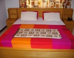 a bed with a colorful blanket on top of it at Calabash Green Executive Apartments in Accra
