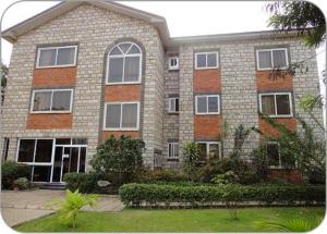 un gran edificio de ladrillo con ventanas y arbustos en Calabash Green Executive Apartments, en Accra