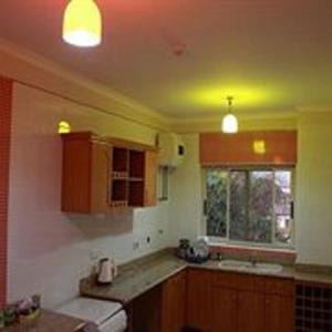 una cocina con armarios de madera y una ventana con luces en Calabash Green Executive Apartments, en Accra