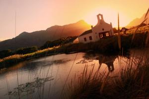 a church sitting on the side of a lake at sunset at Le Manoir de Brendel in Franschhoek