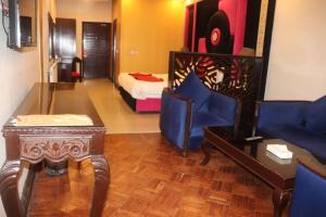 a living room with a bed and a table and blue chairs at Shangrila Hotels and Resort in Murree