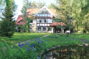 ein Haus mit einem Teich davor in der Unterkunft Villa Rosa in Mezowo