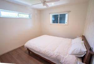 a white bedroom with a bed and a window at Hakuba View Villa in Hakuba