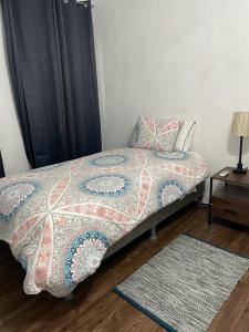 a bedroom with a bed with a quilt and a rug at SERENADE Lodging Rooms in Panama City