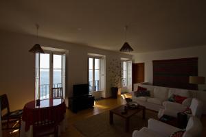 a living room with a white couch and a table at Casa do Lado in Povoação