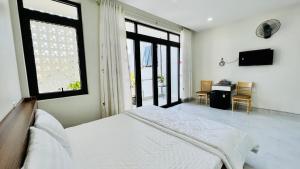 a bedroom with a bed and a desk and windows at Cô Ba Homestay in Quy Nhon