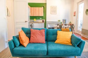 - un canapé bleu avec des oreillers colorés dans le salon dans l'établissement Le Repaire - Appartement spacieux 2 chambres avec balcon, à Marseille