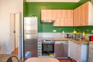 eine Küche mit grünen Wänden und einem Kühlschrank aus Edelstahl in der Unterkunft Le Repaire - 2 chambres avec balcon in Marseille