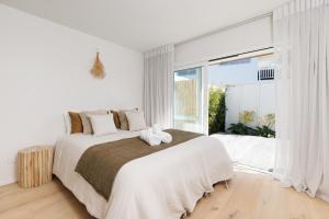 a white bedroom with a large bed and a large window at The Endless Summer Home - Beach and Town Location in Mount Maunganui