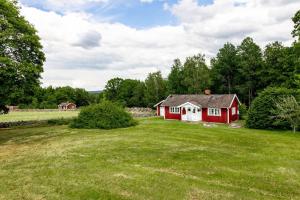 a red house in the middle of a grass field at Nice cottage in Sjuhult with proximity to Lake Rymmen in Rydaholm