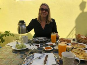 une femme assise à une table avec de la nourriture pour le petit déjeuner dans l'établissement Dar Chez Khadija, à Fès