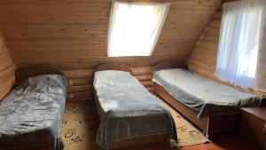 two beds in a log cabin with a window at Гостевой дом Коль-тор in Kegeti