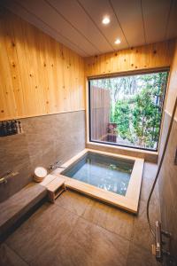 a bathroom with a swimming pool with a window at SAUNA FOREST CABIN 軽井沢 御代田　MORI-ASOBI in Oiwake
