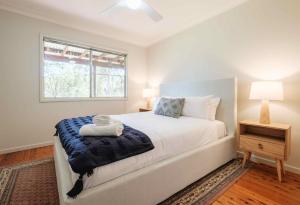 a bedroom with a bed with a blue blanket and a window at Yarramie in Mount View