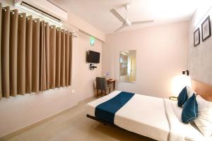 a hotel room with a bed and a desk at FabHotel Azure Sky Hussainpur in Kolkata