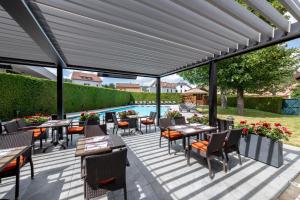 un patio con tavoli, sedie e piscina di Le Grand Hotel & Spa a Gérardmer