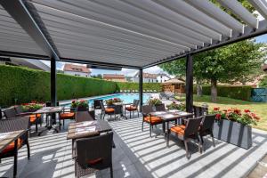 une terrasse avec des tables et des chaises ainsi qu'une piscine dans l'établissement Le Grand Hotel & Spa, à Gérardmer