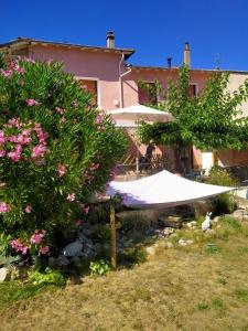 un parasol blanc, des fleurs et un bâtiment dans l'établissement Chambre d'hôtes Juline, 