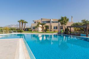 a large blue swimming pool with a building in the background at Serenity Villa with pool, Kalesa Heraklion in Yiofirákia