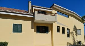 a white house with a balcony on top of it at Villa Toti in Montepaone