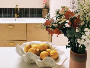 a bowl of oranges on a table with a vase with flowers at Luxury bolthole in central St.Agnes with parking. in St. Agnes