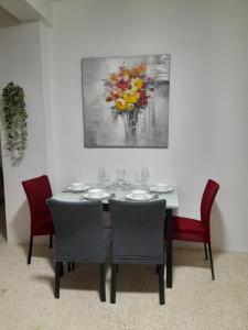 une table à manger avec des chaises et un tableau mural dans l'établissement Gozo Marsalforn, à Marsalforn