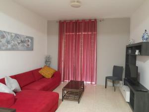 un sofá rojo en la sala de estar con una cortina roja en Gozo Marsalforn, en Marsalforn