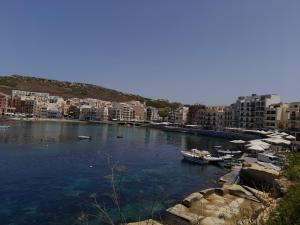 a river with boats in a city with buildings at Gozo Marsalforn in Marsalforn