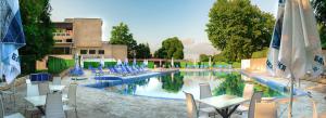 ein großer Swimmingpool mit Liegen und Sonnenschirmen in der Unterkunft Хотел България Петрич in Petrich