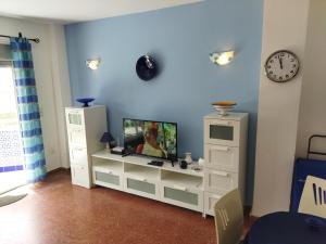 una habitación con un centro de entretenimiento blanco con TV en Torresol 208, en Nerja