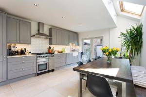 una cucina con armadi grigi e tavolo con sedie di ALTIDO 3-bedroom family home w/ garden a Londra