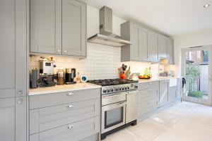 a kitchen with white cabinets and a stove top oven at ALTIDO 3-bedroom family home w/ garden in London