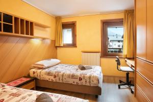 a bedroom with two beds and a desk and a window at Casa Marmut in Livigno