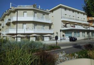 a large white building with balconies on a street at Hotel Gabbiano in Rimini