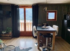 uma cozinha com uma mesa num quarto com uma janela em Fleur et Benj em Aussois