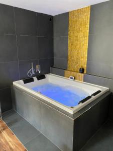 a large tub in a bathroom with blue water at FiftyShades Apartmán s vířivkou in Jihlava